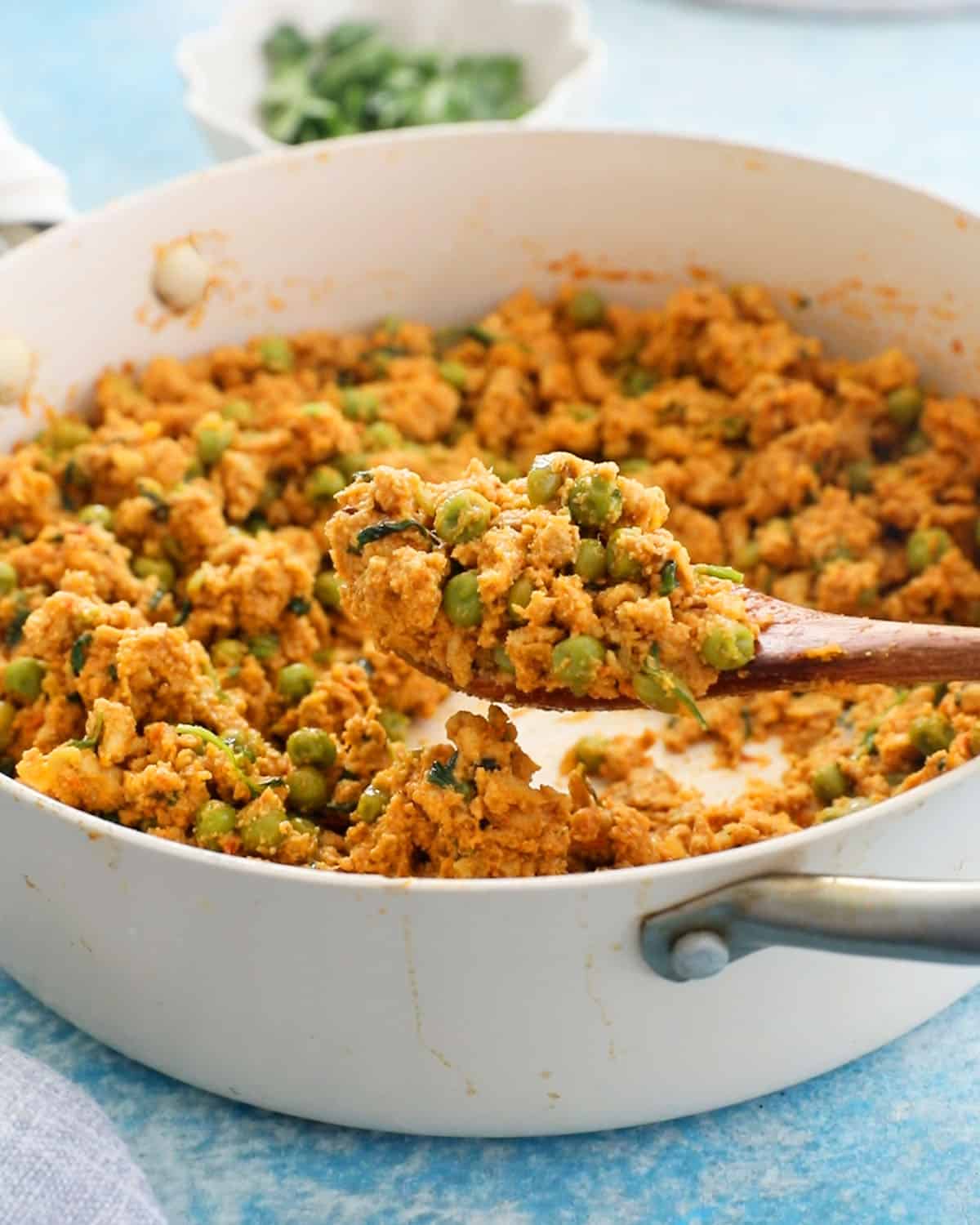 brown chicken keema matar in a white pan.