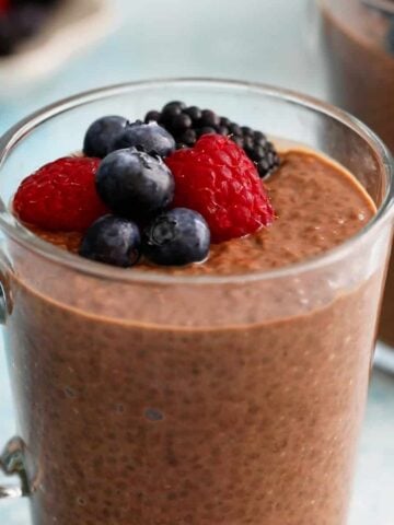 chocolate chia pudding topped with berries in a glass jar.