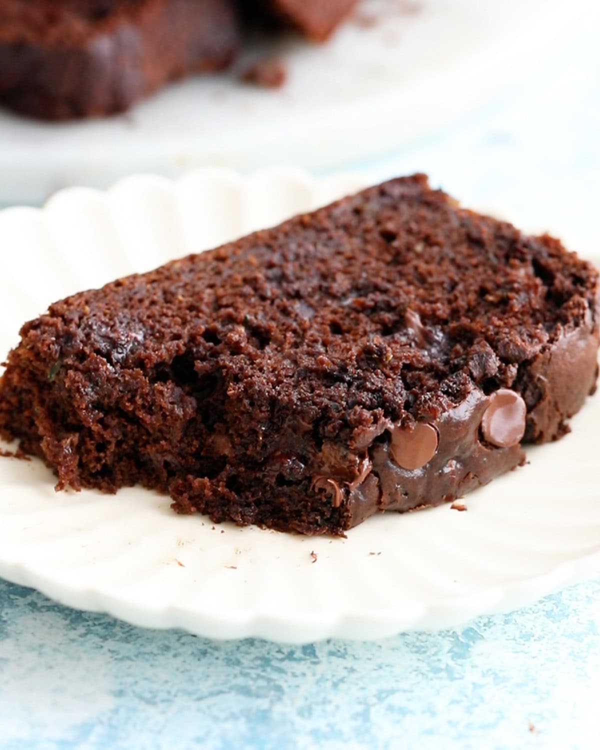 a slice of brown chocolate zucchini bread in a white plate.