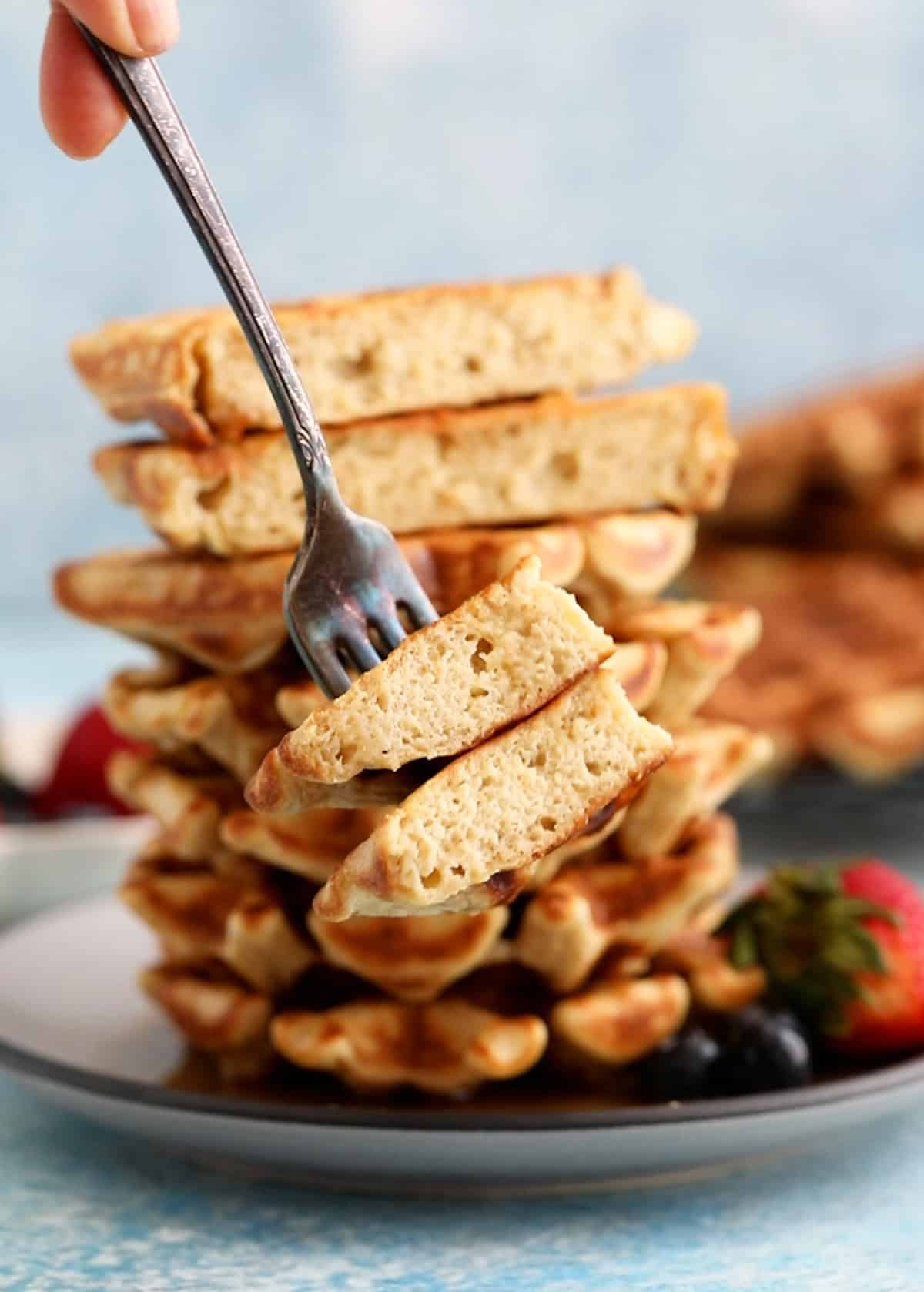 6 cottage cheese waffles stacked on a grey plate.