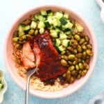 cooked firecracker salmon, veggies and quinoa in a pink bowl.