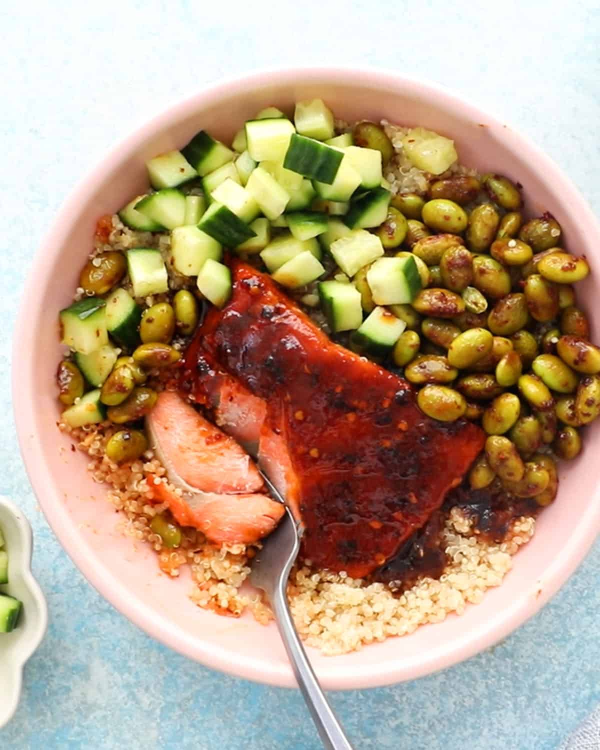 cooked firecracker salmon, veggies and quinoa in a pink bowl.