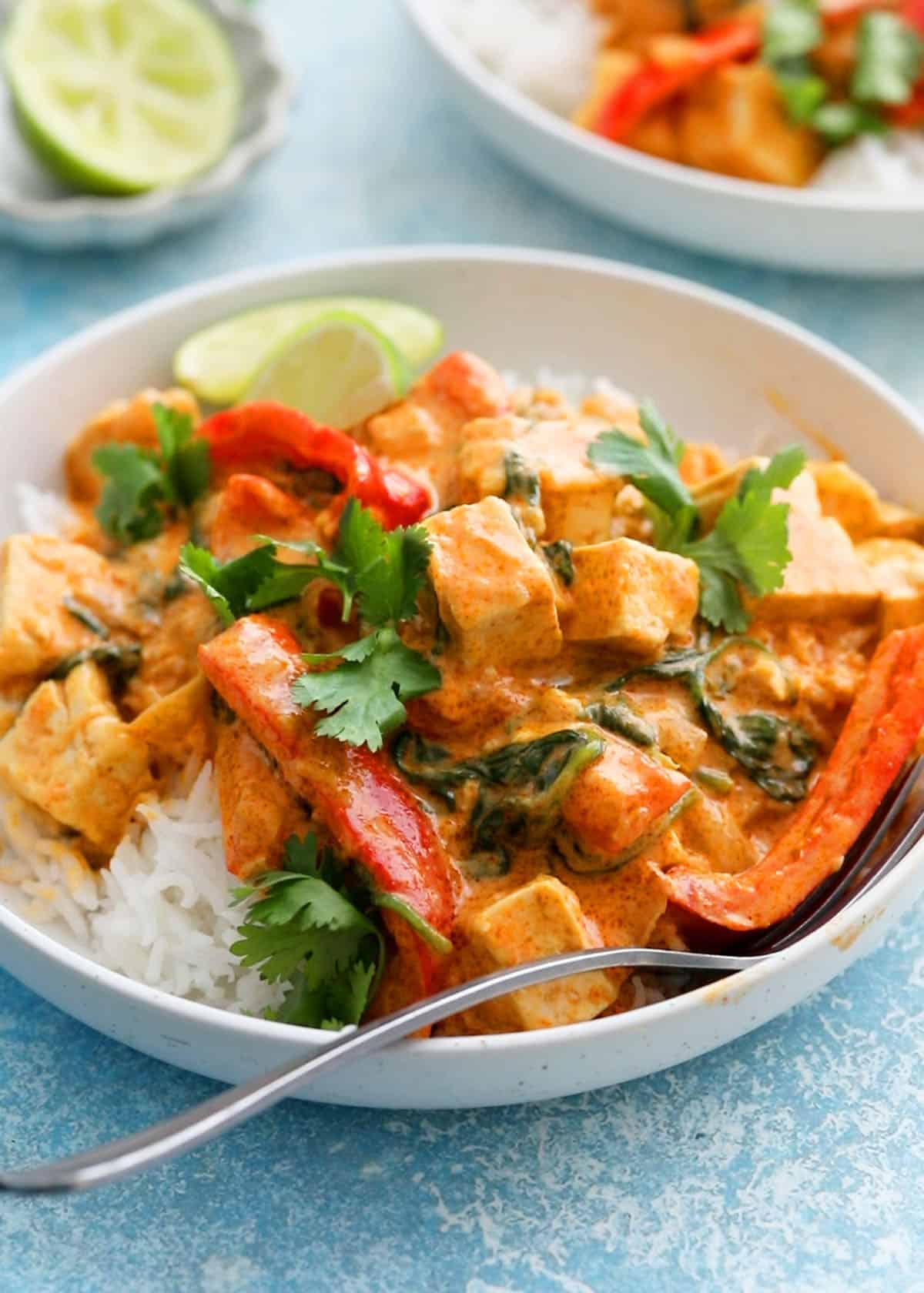 Thai red tofu curry with white rice in a white bowl.