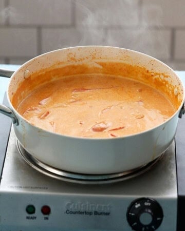 thai red curry cooking in a white pan.