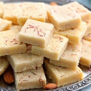 badam burfi piled high on a metal plate.