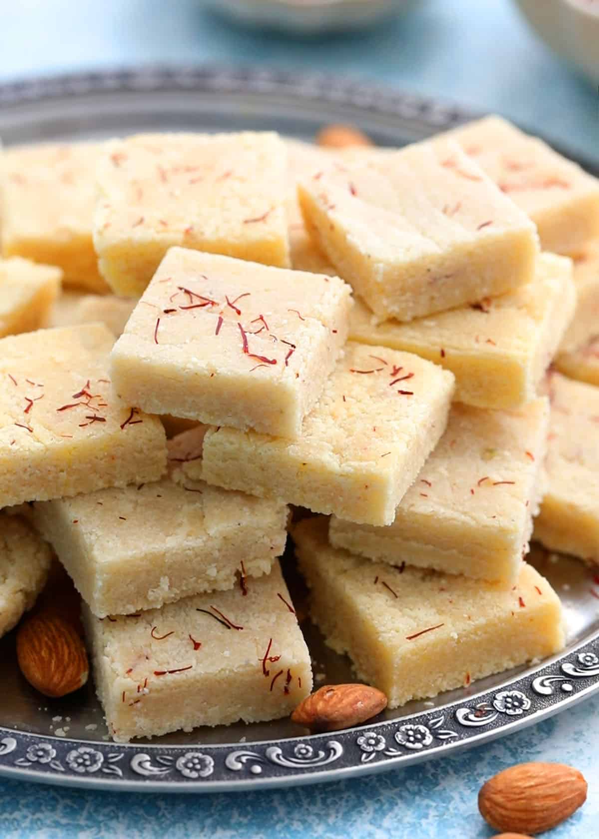 badam burfi piled high on a metal plate.