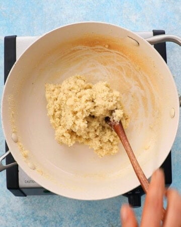 badam burfi cooking in a white pan.