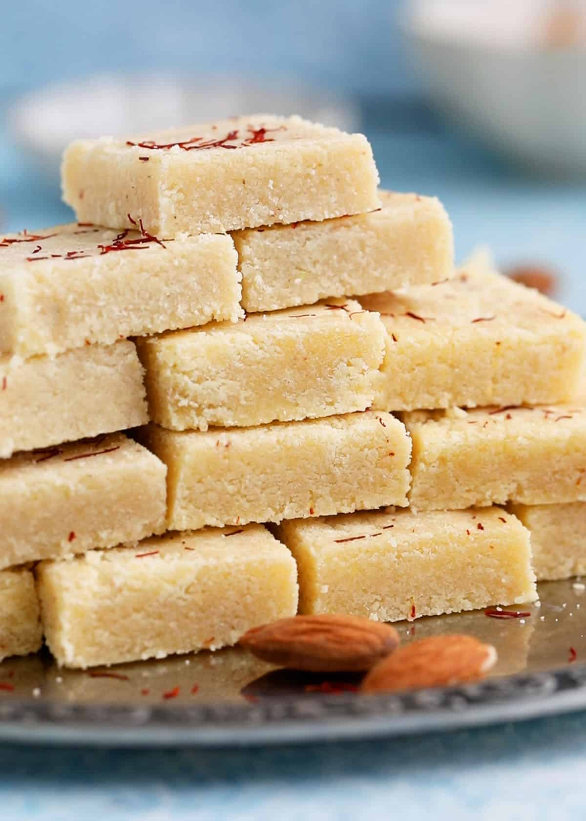 badam burfi piled high on a metal plate.