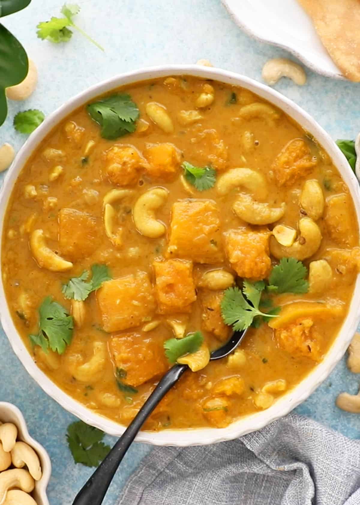 one white bowl filled with orange butternut squash curry.