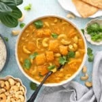 one white bowl filled with orange butternut squash curry.