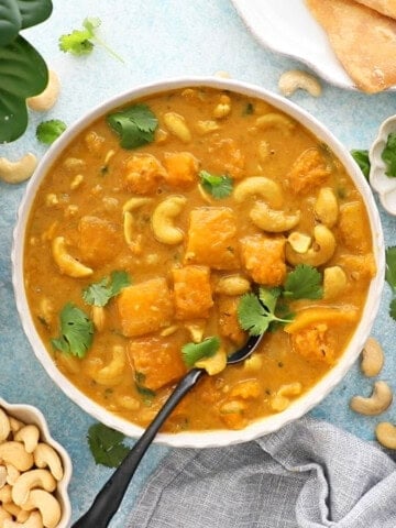 one white bowl filled with orange butternut squash curry.