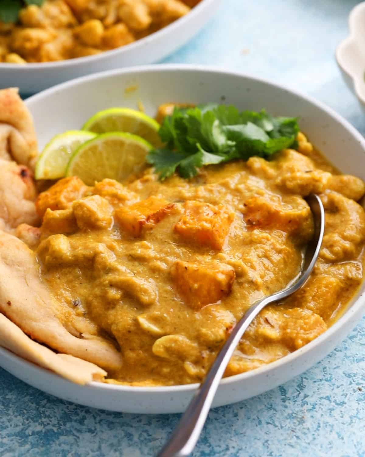 butternut squash curry along with naan in a white bowl.