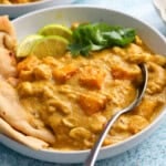 butternut squash curry along with naan in a white bowl.