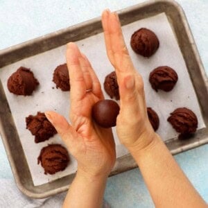 two hands rolling brown cookie dough.