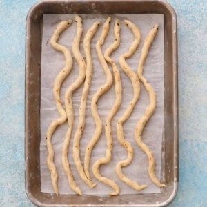 8 white snakes in a metal baking sheet.