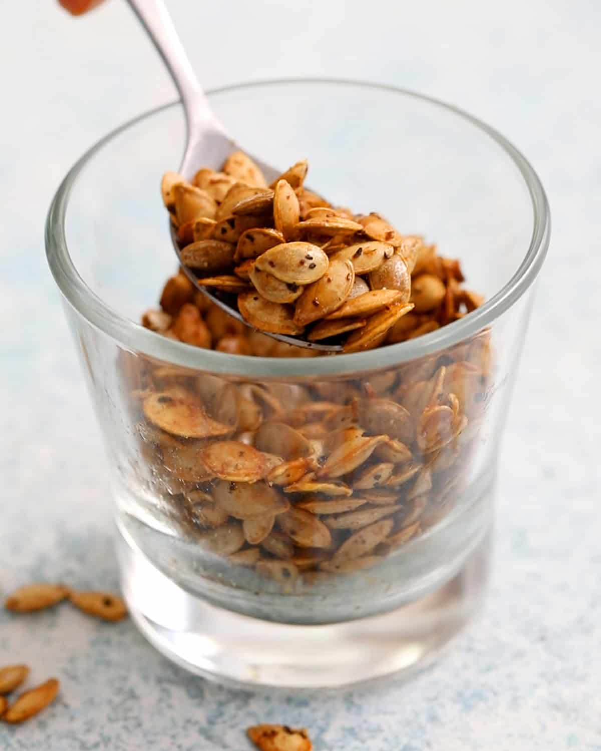 roasted butternut squash seeds in a small glass cup.