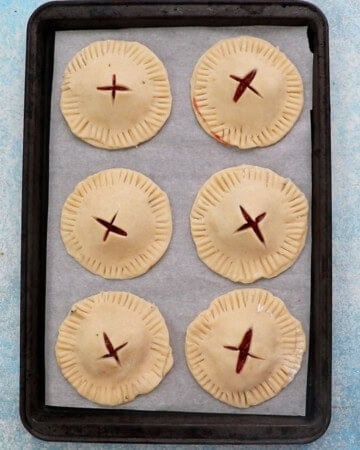 6 round apple cranberry pie on a baking sheet.