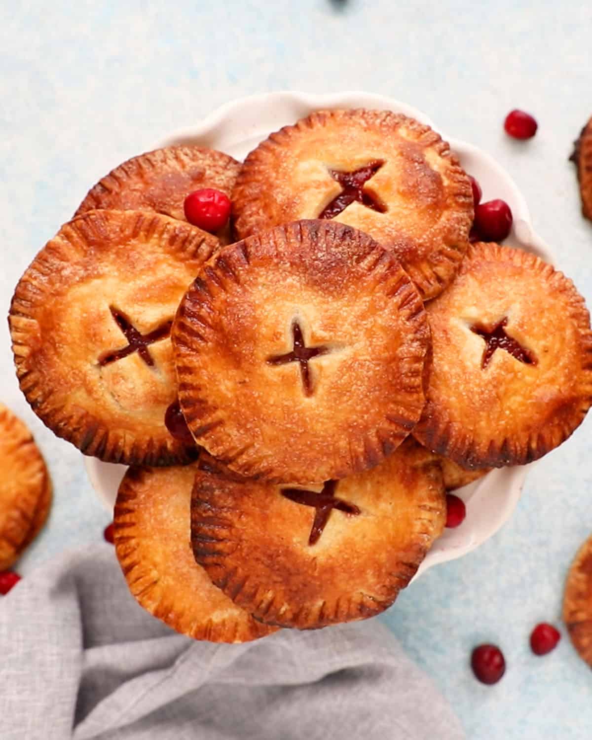 apple cranberry hand pies on a white cake stand.