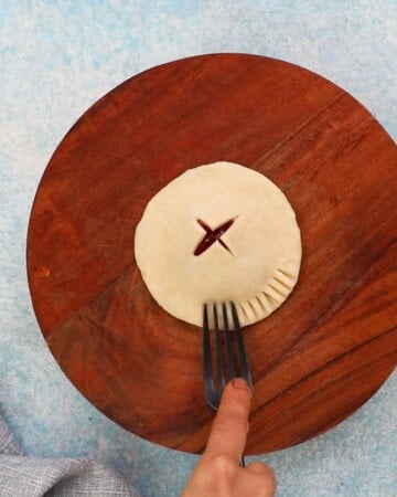 one round apple cranberry pie on a wooden board.