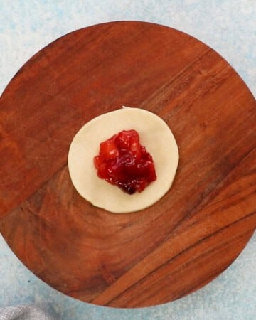 one round apple cranberry pie on a wooden board.