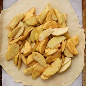 one unbaked apple galette on a white paper.