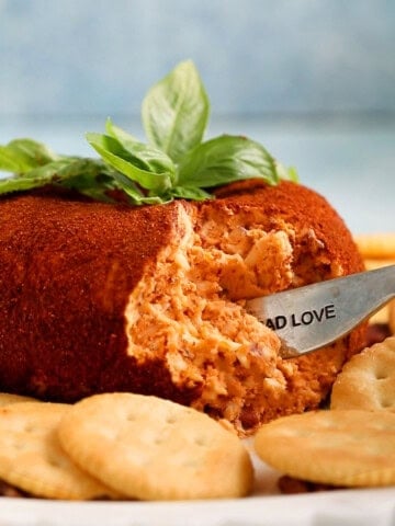 one tomato shaped cheese ball on a white platter.