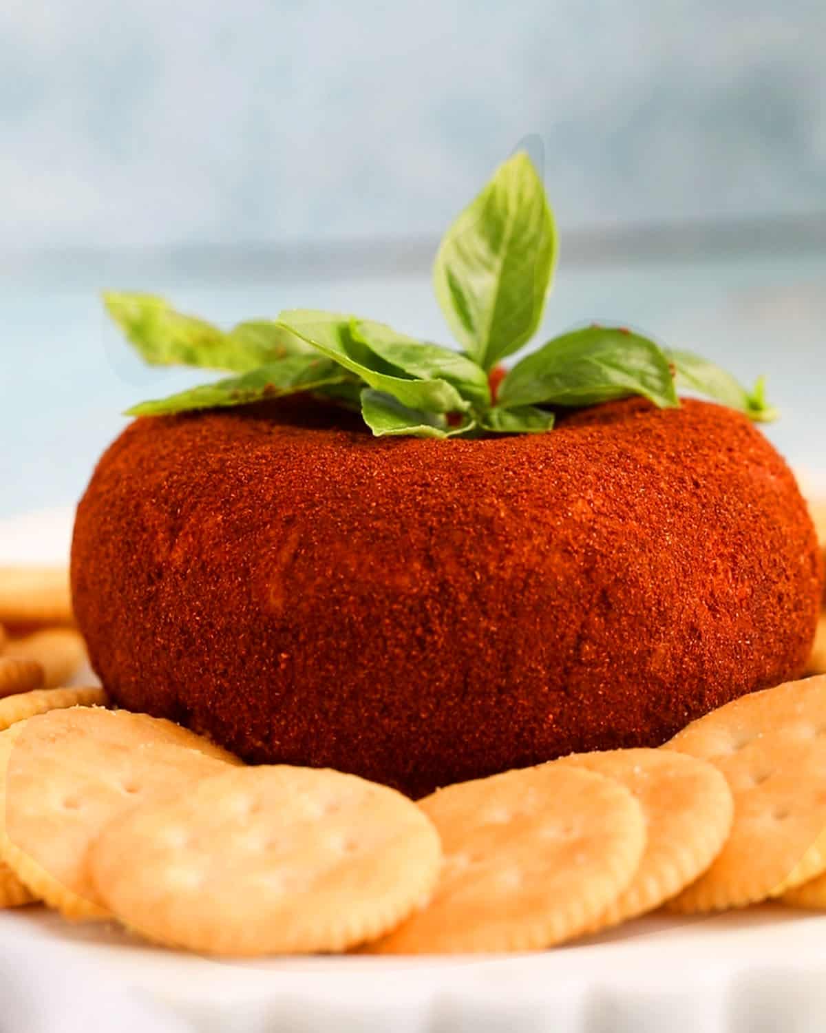 one tomato shaped cheese ball on a white platter.
