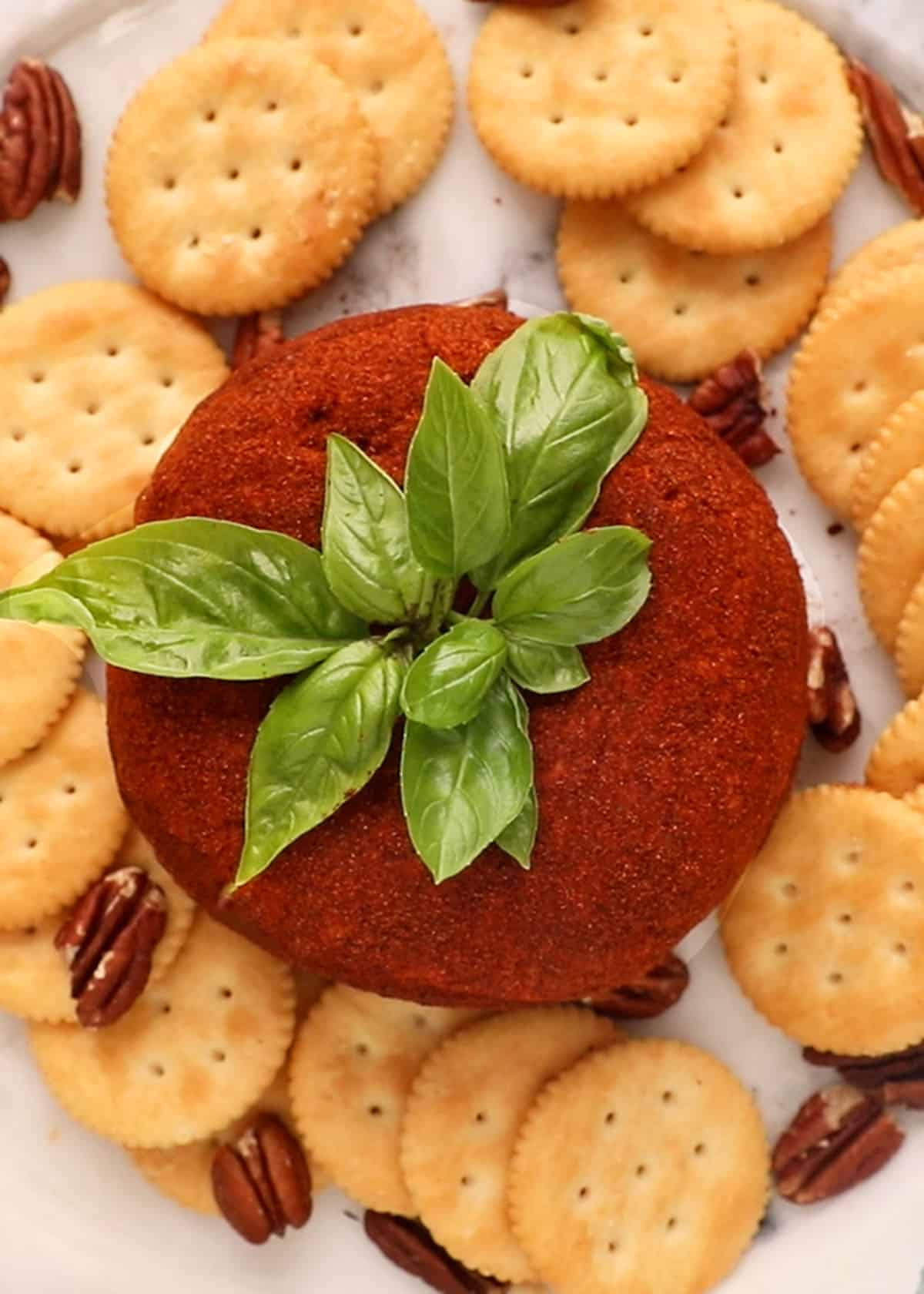 one tomato shaped cheese ball on a white platter.