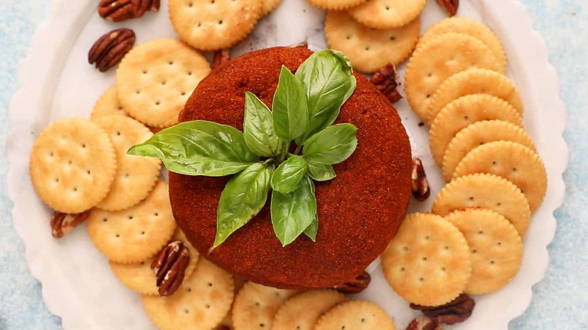 one tomato shaped cheese ball on a white platter.