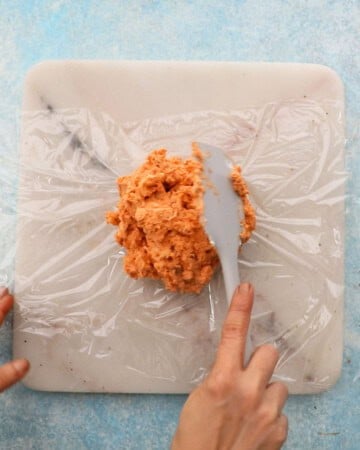 pink tomato cheese ball mixture in plastic wrap.