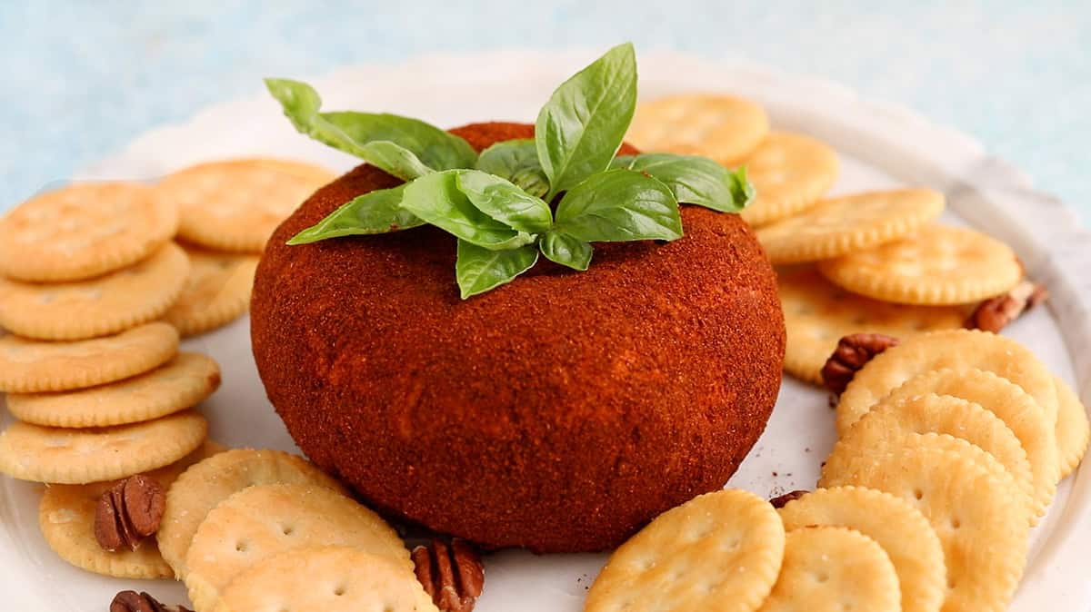 one tomato shaped cheese ball on a white platter.