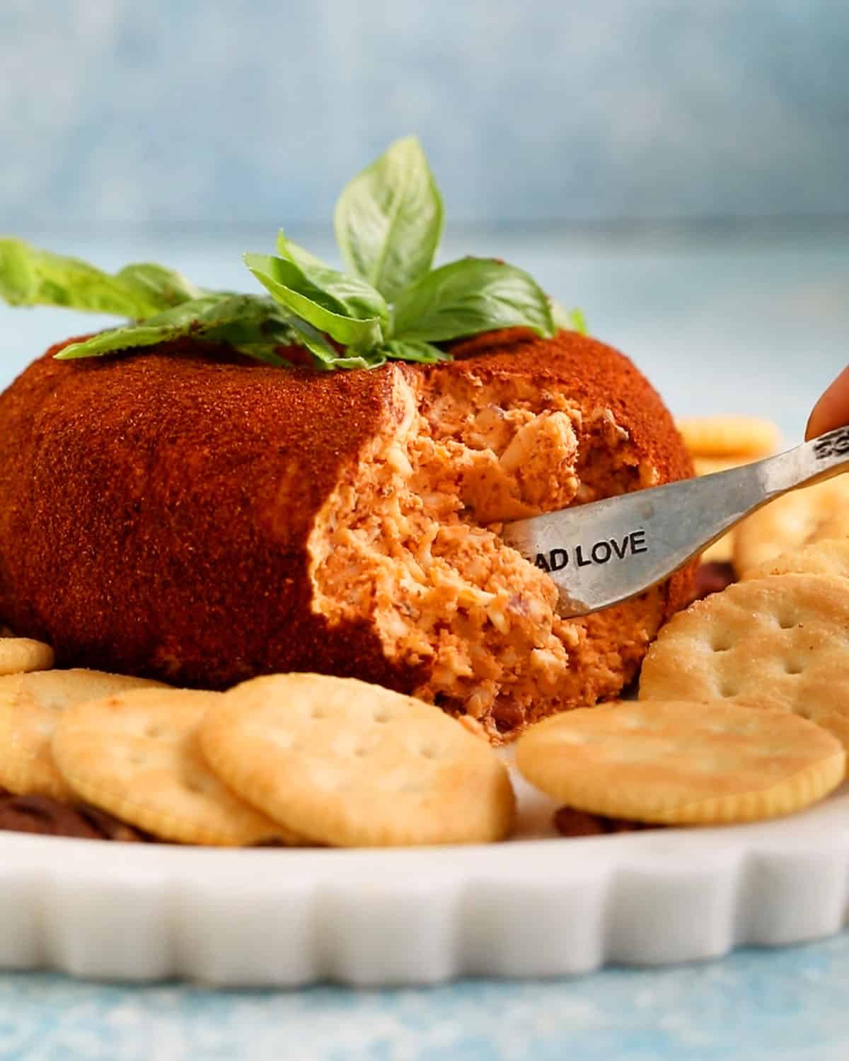one tomato shaped cheese ball on a white platter.