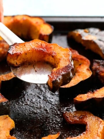 roasted acorn squash on a black baking sheet.