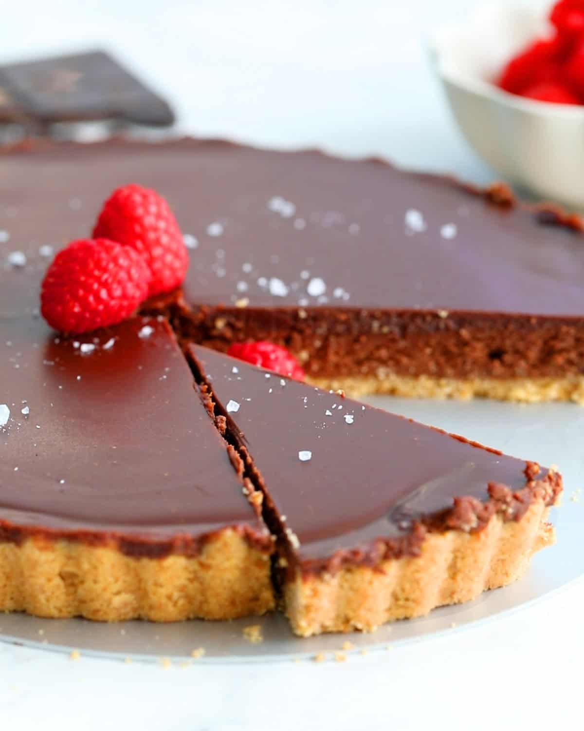 one brown chocolate tart topped with raspberries.