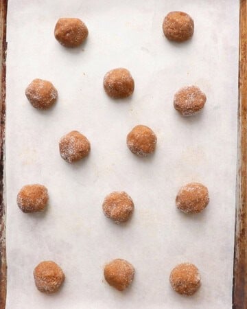 brown ginger molasses cookie dough balls in a white baking sheet.