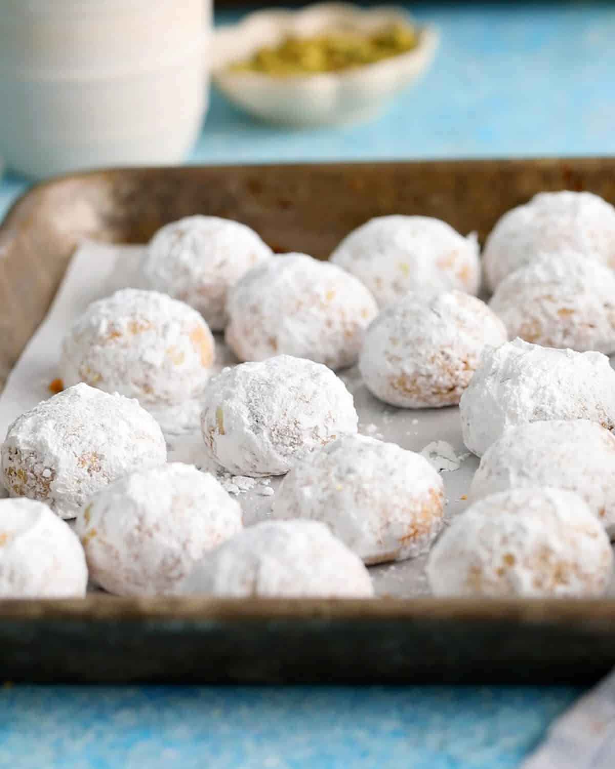 almond flour pistachip snowball cookies on a metal tray.