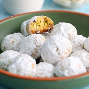 almond flour pistachio snowball cookies in a green bowl.