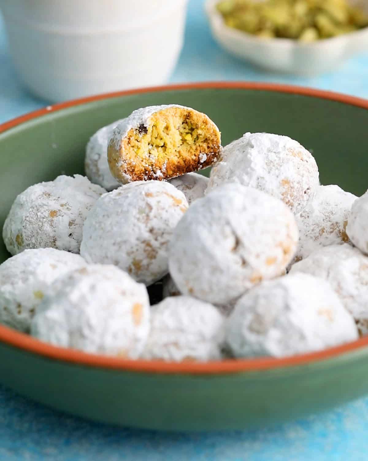 almond flour pistachip snowball cookies in a green bowl.
