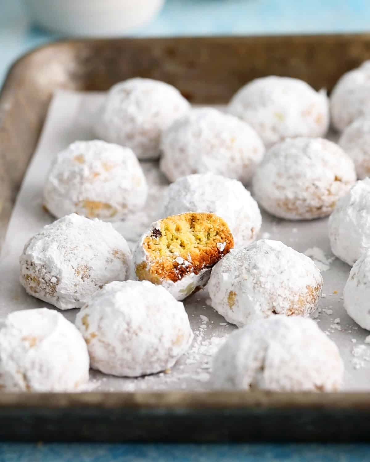 almond flour pistachip snowball cookies on a metal tray.