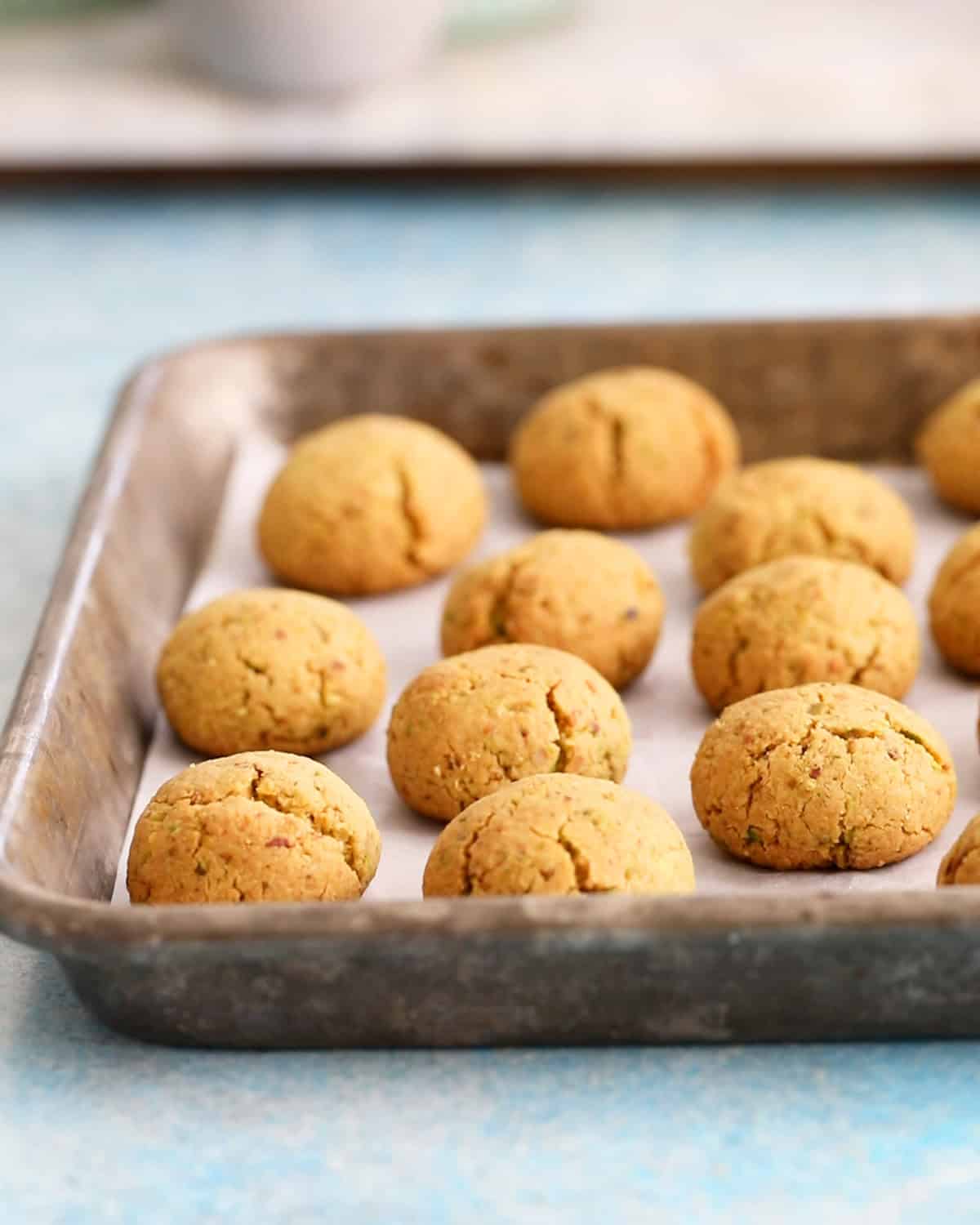 almond flour pistachip snowball cookies on a metal tray.