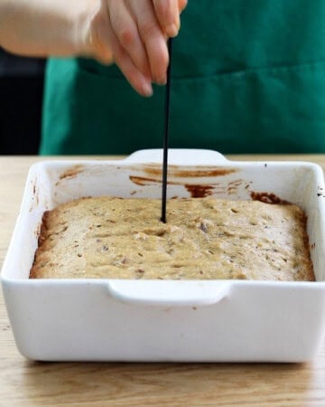 brown date cake in a white baking dish.