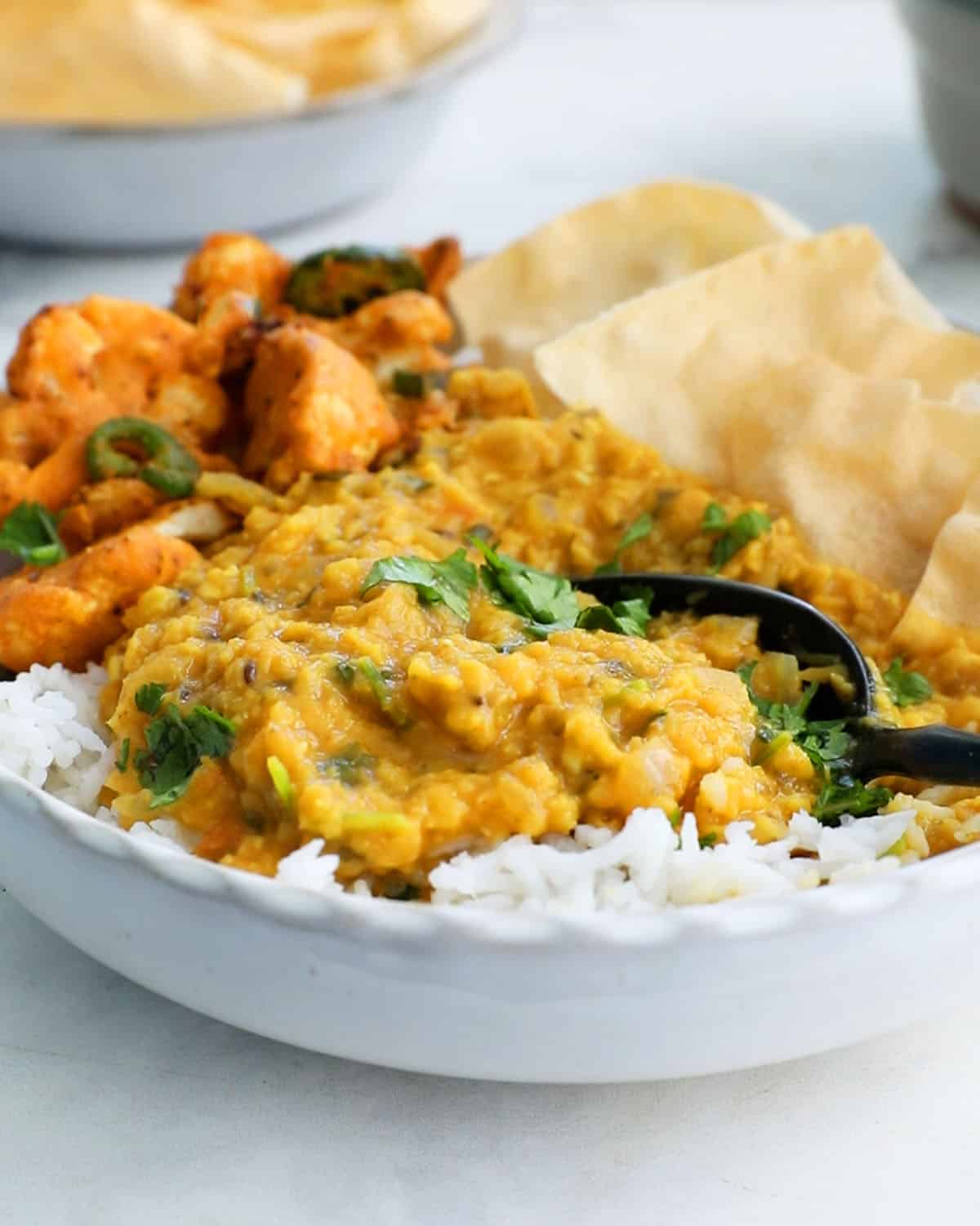 red lentil dal with white rice in a white bowl.