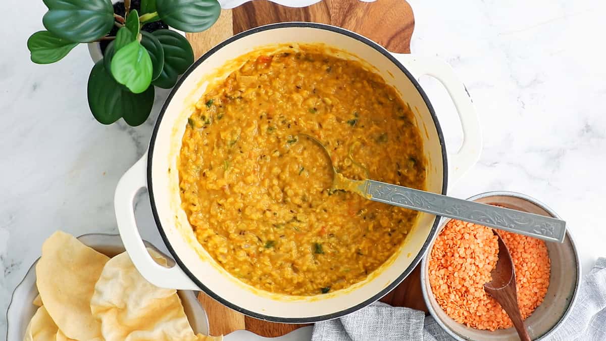 red lentil dal curry in a white pot.