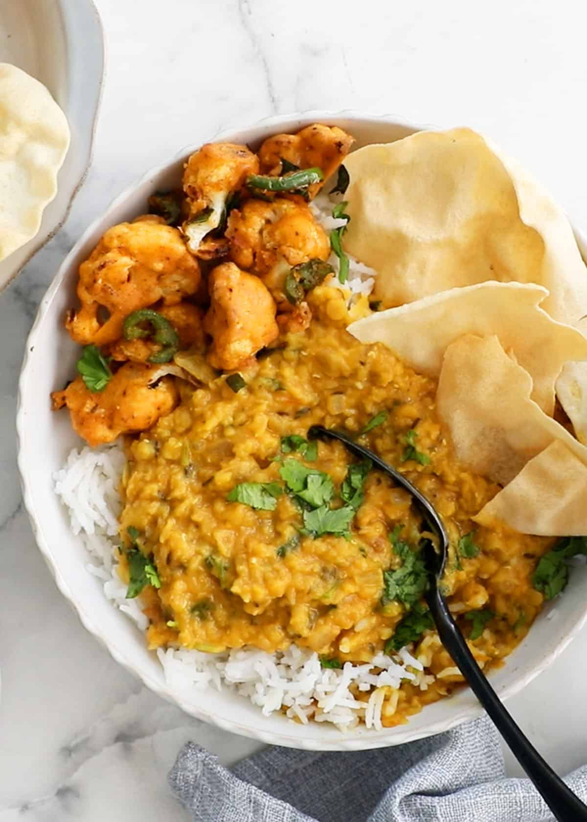 red lentil dal with white rice in a white bowl.