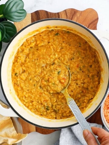 red lentil dal curry in a white pot.