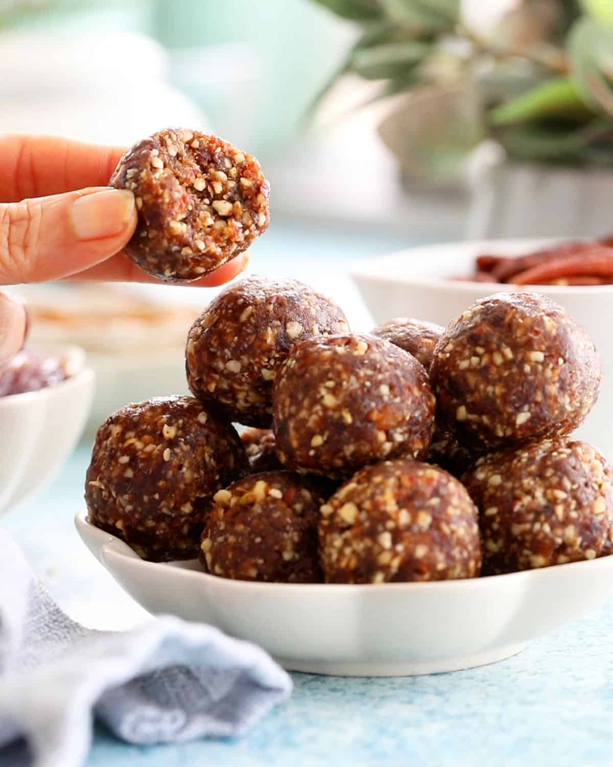 a hand holding one brown pecan date ball.