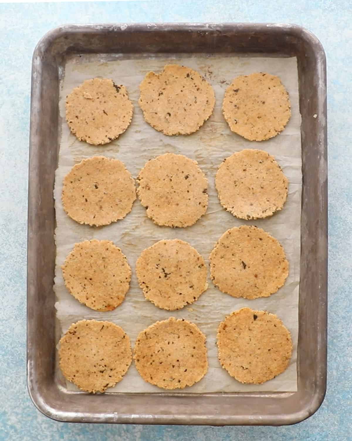 12 round almond flour crackers in a metal baking sheet.