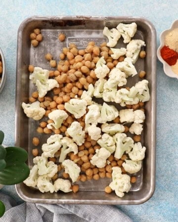 chopped white cauliflower and chickpeas in a metal sheet pan.