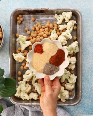 chopped white cauliflower and chickpeas in a metal sheet pan.