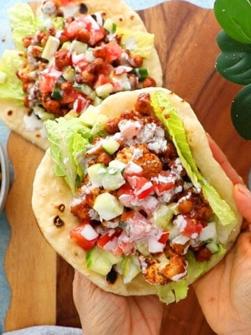 two hands holding a chickpea and cauliflower wrap.